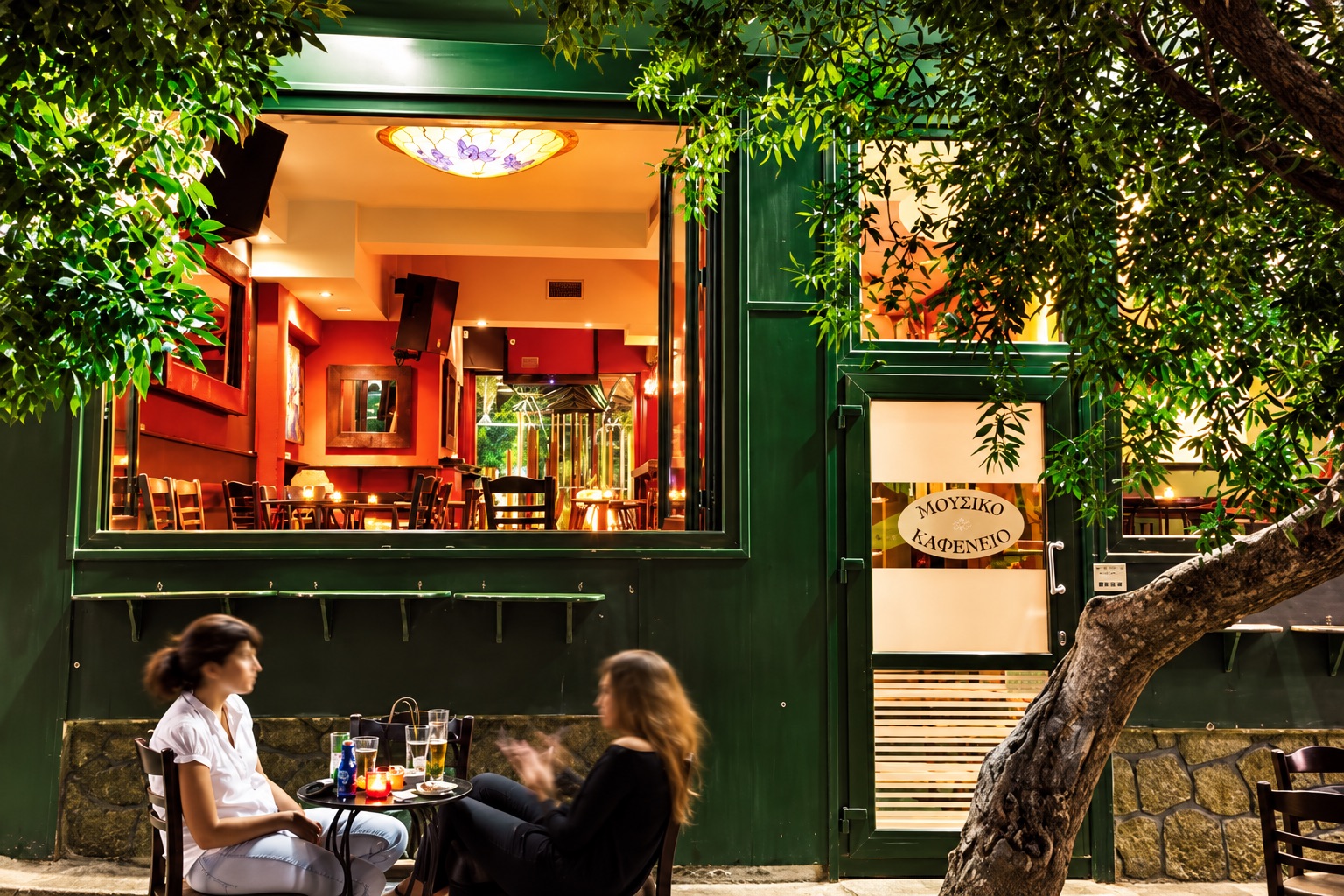 The warm atmosphere of Mousiko Kafeneio at night, with friends and music